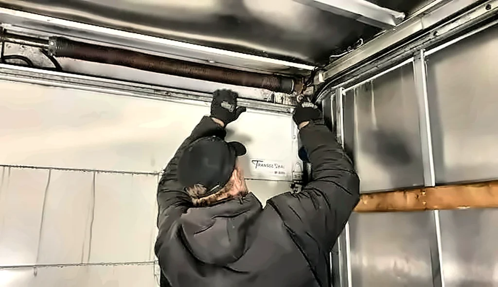 Technician inspecting garage door springs before winter